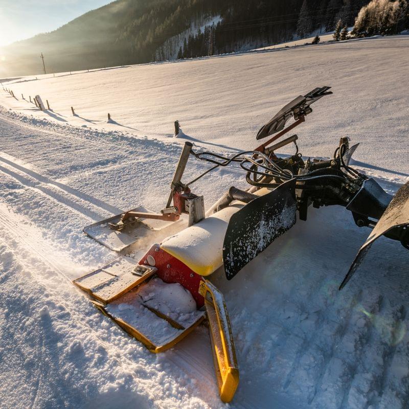 Snow grooming machine preparing cross-country ski trail at sunrise